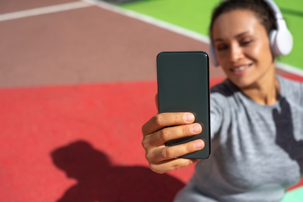 El teléfono inteligente en la mano de una mujer con auriculares blancos