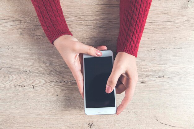 Teléfono inteligente de mano de mujer en el escritorio