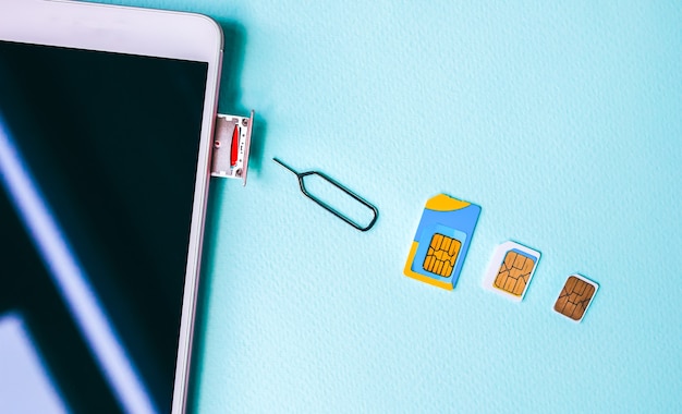 Foto teléfono inteligente moderno sobre la mesa. diferentes tarjetas micro y nano sim cercanas. diferentes generaciones en tecnologías de la comunicación.