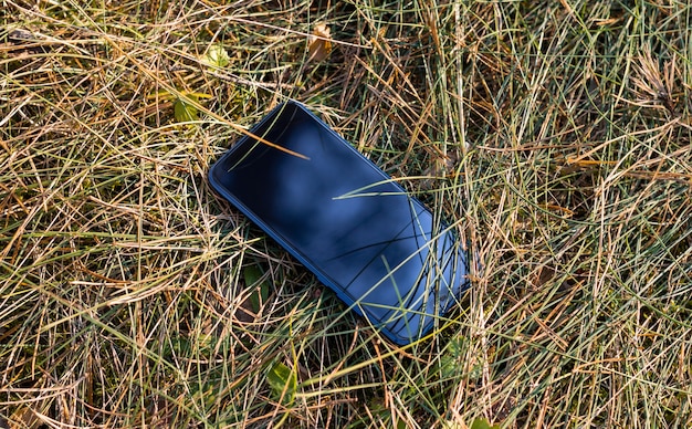 Teléfono inteligente móvil en la hierba - teléfono perdido