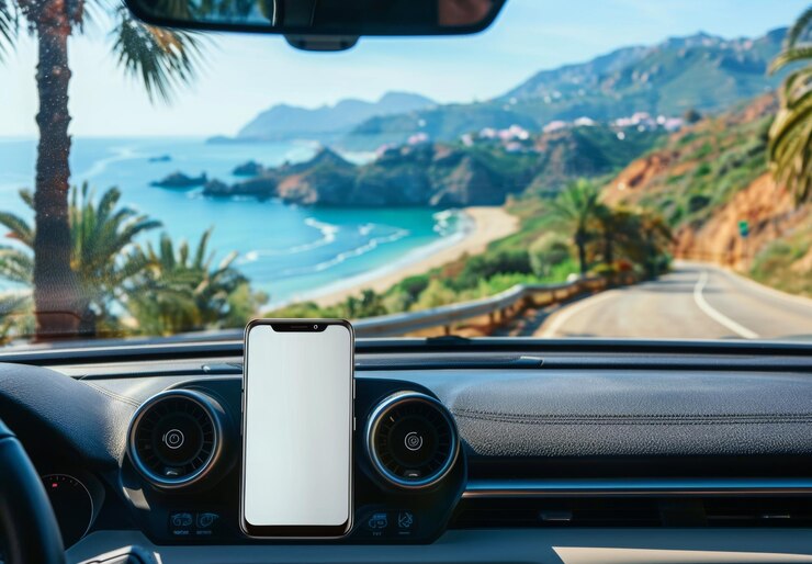 Un teléfono inteligente de pantalla blanca en blanco en un tablero de instrumentos de coche con una carretera panorámica visible a través del parabrisas