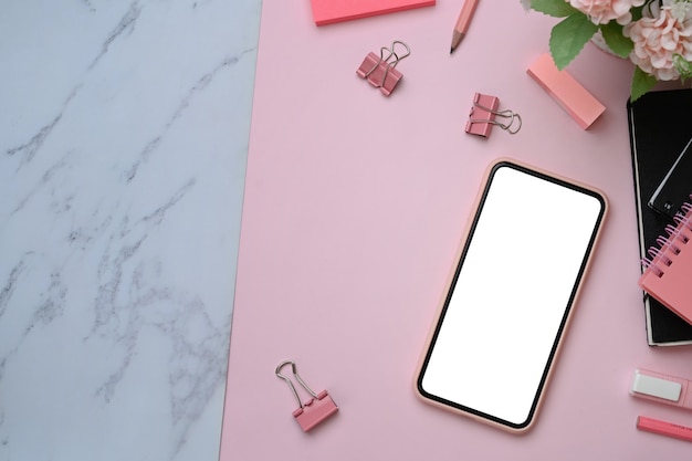 Teléfono inteligente con pantalla en blanco sobre fondo rosa y mármol.