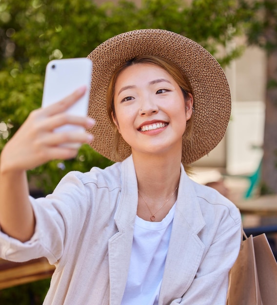 Teléfono inteligente Selfie y bolsa de compras de mujer en la ciudad o parque para publicación en redes sociales, actualización de imagen de perfil y blog de moda en Japón Fotografía de teléfono celular mujer feliz o influenciadora con consejos minoristas