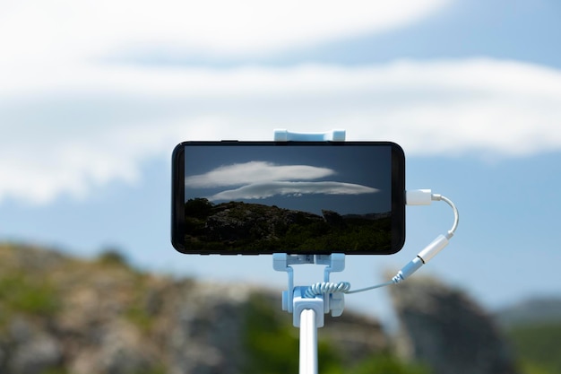 Un teléfono inteligente en un selfie stick fotografía un fenómeno raro: la nube lenticular Fotografía móvil mientras viaja