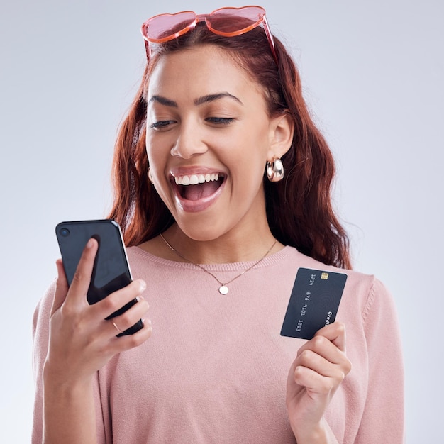 Foto teléfono de inversión o niña feliz con tarjeta de crédito para inversión en línea en fintech digital en estudio pago de comercio electrónico de aplicación móvil financiera o mujer emocionada de la generación z escribiendo datos bancarios en internet