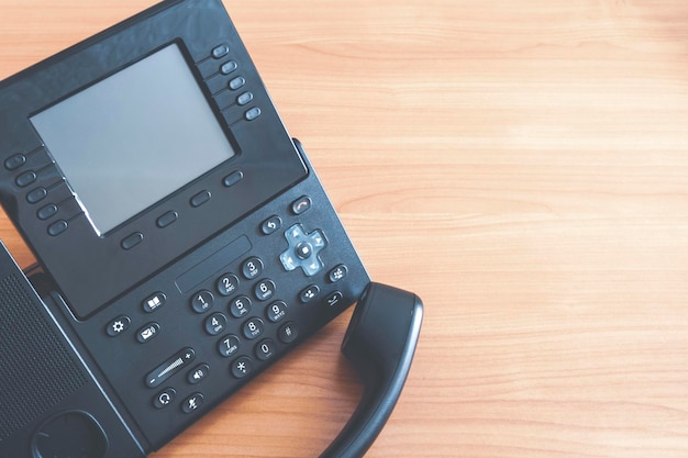 El teléfono IP con pulsador de escritorio negro en el escritorio en el concepto de comunicación de la oficina de cerca
