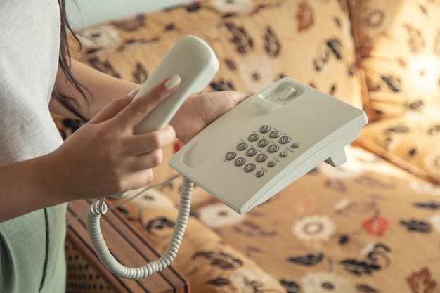 Foto teléfono de llamada de mano de mujer en la habitación del hotel