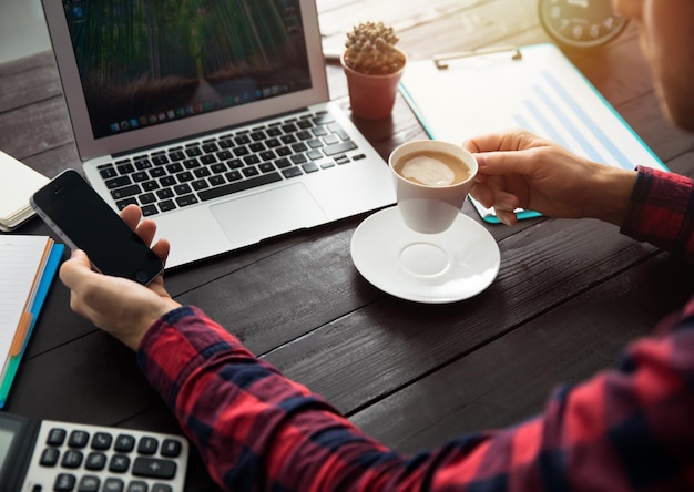 Teléfono de mano de hombre con café y teclado