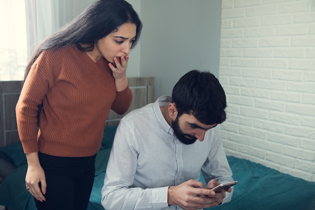 Foto teléfono de mano de hombre con mujer enojada en la habitación