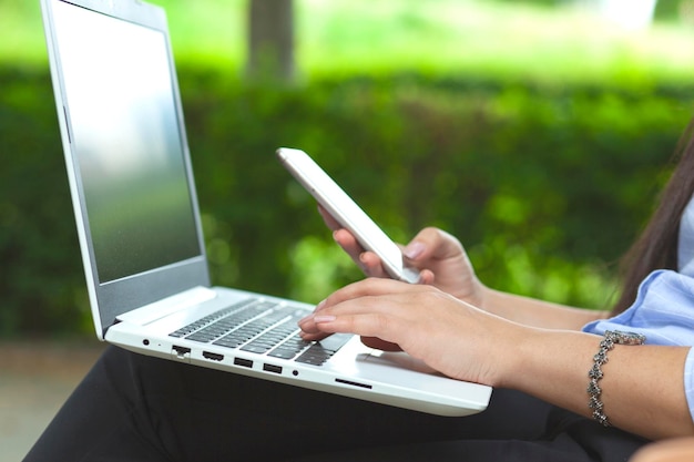 Teléfono de mano de mujer y trabajando en computadora