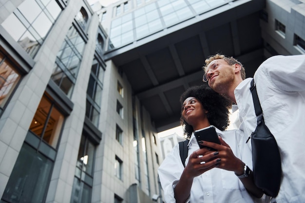 Foto con teléfono en manos hombre con mujer afroamericana juntos en la ciudad al aire libre