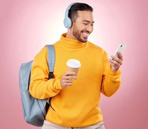 Teléfono de mochila y hombre escuchando auriculares o viajes de podcast universitarios y café sobre fondo rosa E aprendizaje móvil y persona con bolsa de música o transmisión de audio y chat universitario en estudio