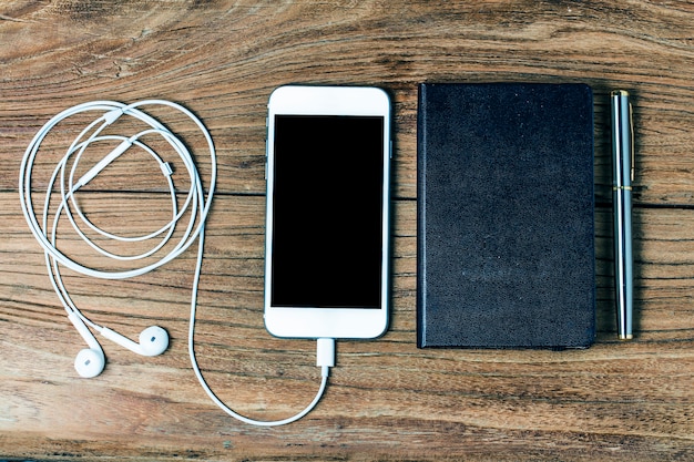 Teléfono móvil y auriculares sobre fondo de madera