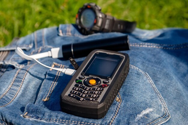 Un teléfono móvil y un banco de energía en un jeans en el reloj de fondo