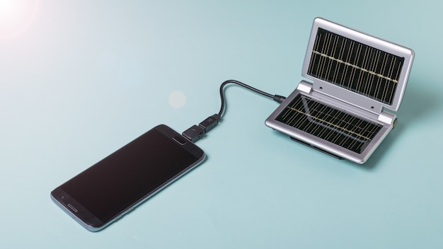 El teléfono móvil se carga con un cargador portátil de energía solar. Uso de energía solar. Tecnología del futuro.