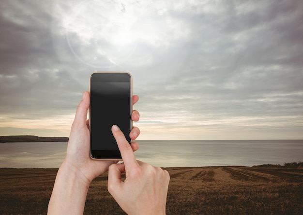 Teléfono móvil conmovedor de la mano con paisaje de cielo nocturno