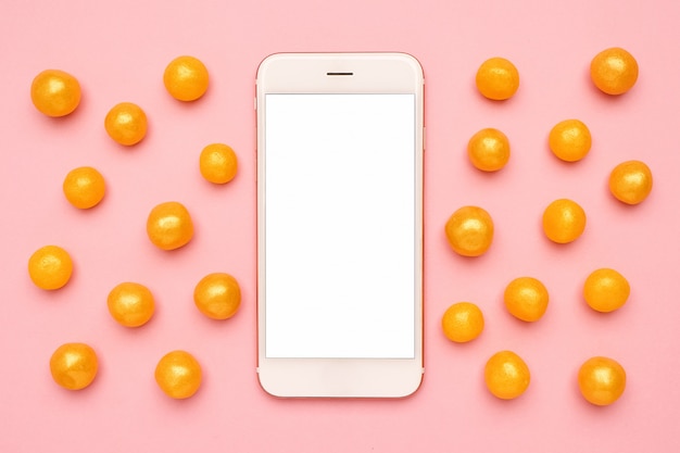 Teléfono móvil y dulces dulces amarillos en una tecnología rosa
