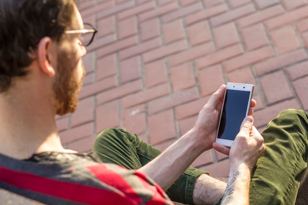 Un teléfono móvil en manos de un hipster. Un joven usa un teléfono inteligente.