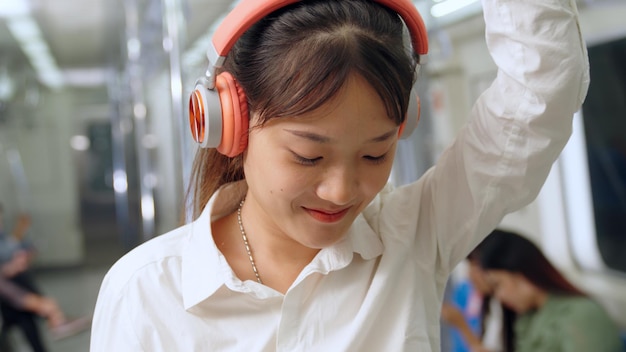 Teléfono móvil de mujer joven en tren público. Concepto de desplazamiento del estilo de vida urbano de la ciudad.