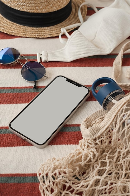 Teléfono móvil de pantalla en blanco con espacio de copia de maqueta Plantilla de marca comercial mínima bohemia estética Elegantes gafas de sol femeninas sombrero de paja bolsa de compras botella de agua