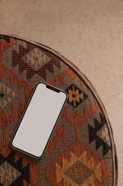 Teléfono móvil con pantalla en blanco sobre una alfombra ornamental tradicional Plantilla de aplicación de sitio web de blog minimalista con vista plana superior Maqueta de espacio de copia