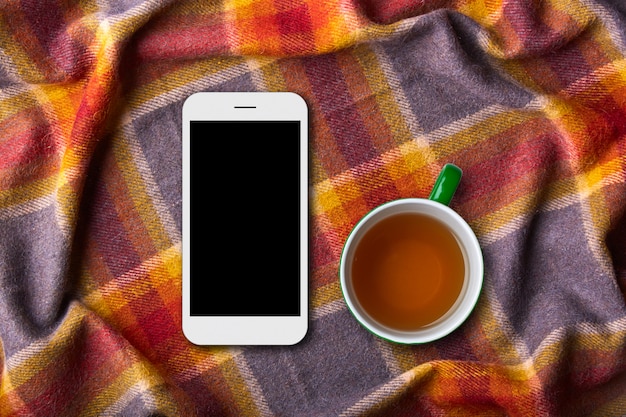 Teléfono móvil y tableta en una cálida manta colorida
