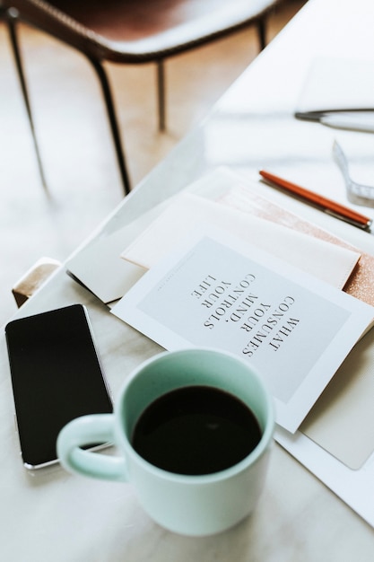 Teléfono móvil con una taza de café y un cuaderno.