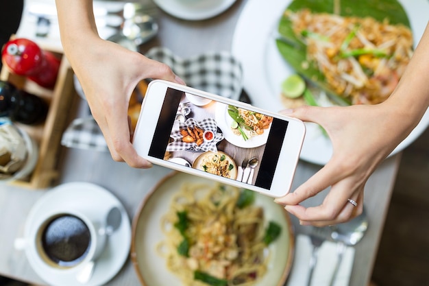 Teléfono móvil tomando fotos en la comida desde arriba en el restaurante