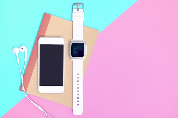 Teléfono móvil vacío con gadgets de smartwatch en azul rosado