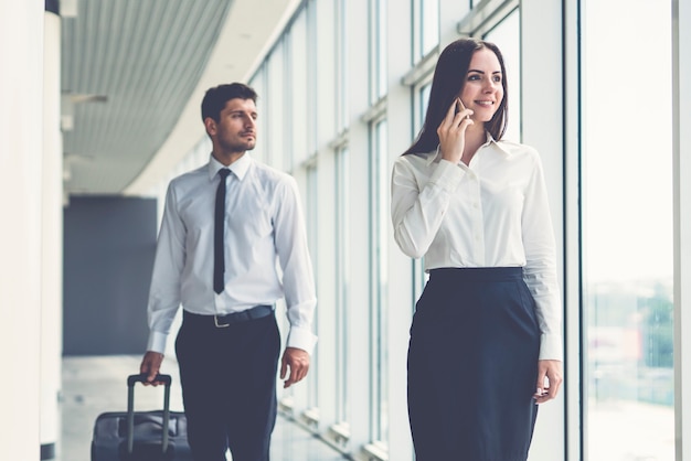 El teléfono de la mujer de negocios cerca del hombre con una maleta.