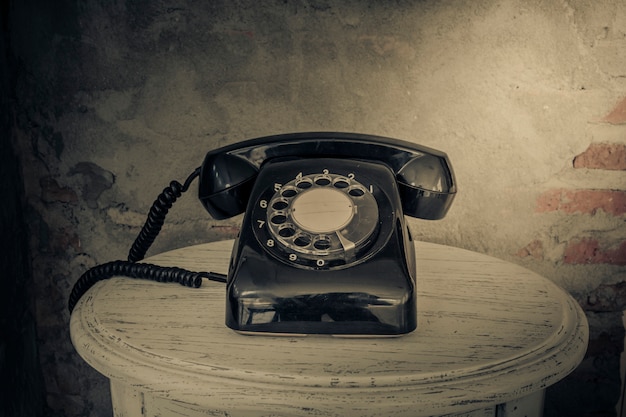 Teléfono negro de la vendimia en el viejo fondo de las paredes