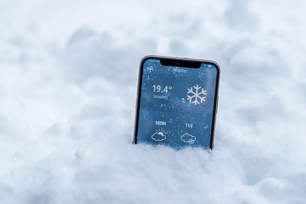 El teléfono en la nieve con un pronóstico del tiempo muestra la temperatura en Fahrenheit