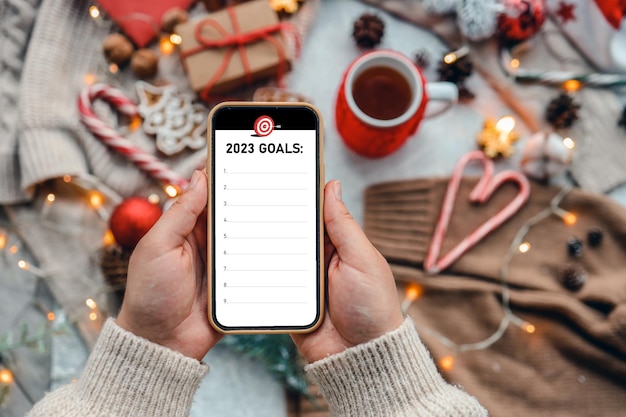 Teléfono con los objetivos de inscripción 2023 en un fondo festivo de Año Nuevo