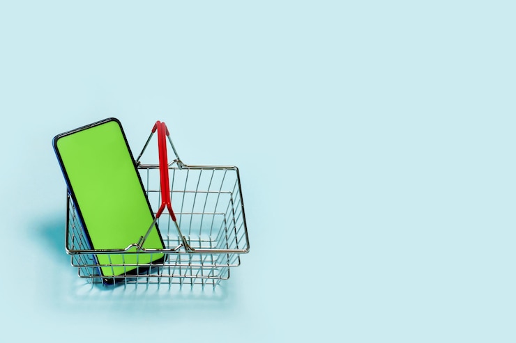 Foto teléfono de pantalla verde en el carrito de compras en un fondo claro con copia de espacio elección de los compradores
