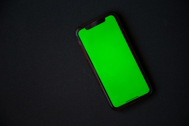 El teléfono con pantalla verde está sobre un fondo negro con una foto de alta calidad.
