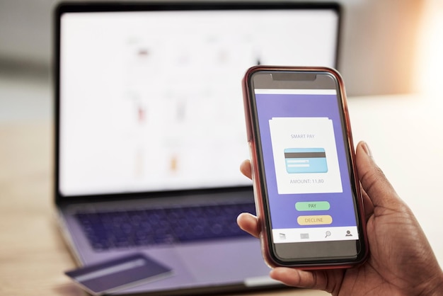 Teléfono de la persona y mano con tarjeta de crédito en el sitio web en pago o transacción de compras en línea en la oficina Primer plano del comprador con débito en la aplicación de teléfono inteligente móvil en compras de comercio electrónico o banca en el escritorio