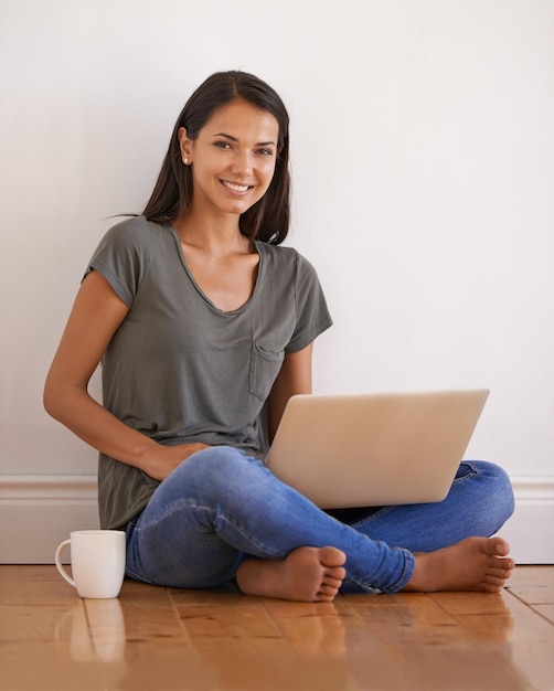 Teléfono portátil de pared y retrato de mujer en el piso con sonrisa apartamento y té o café Felicidad persona femenina y estudiante en la universidad estudiando en línea con tecnología para el examen en una casa nueva