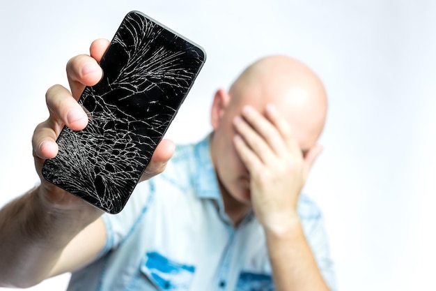 Teléfono con un primer plano de pantalla rota Un hombre blanco sostiene un teléfono inteligente negro con una pantalla rota