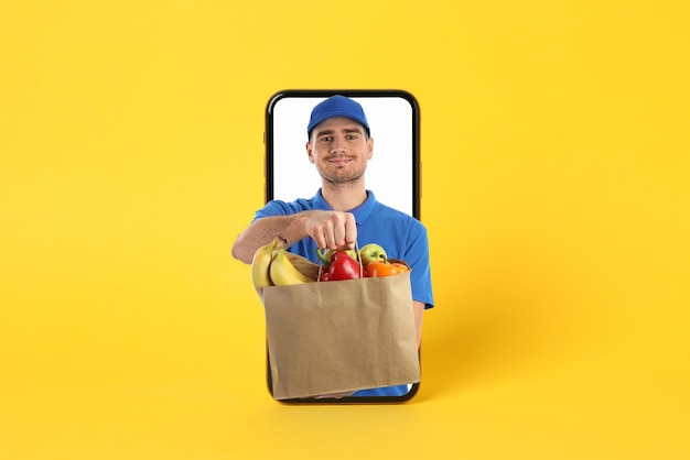 Teléfono con repartidor con comestibles sobre fondo amarillo