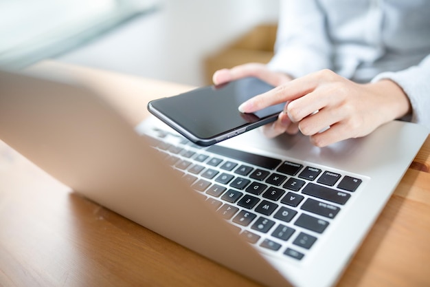 Teléfono táctil de mano de mujer sobre teclado portátil