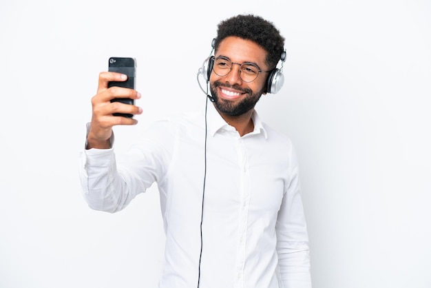 Telemarketer Brasilianischer Mann, der mit einem Headset arbeitet, das auf weißem Hintergrund isoliert ist und ein Selfie macht