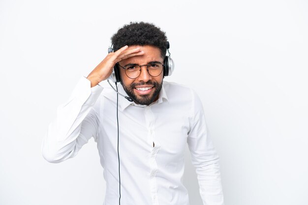 Telemarketer Brasilianischer Mann, der mit einem Headset arbeitet, das auf weißem Hintergrund isoliert ist und mit der Hand weit wegschaut, um etwas zu sehen