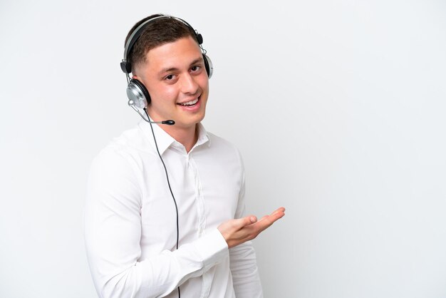 Telemarketer hombre brasileño que trabaja con un auricular aislado sobre fondo blanco que presenta una idea mientras mira sonriendo hacia