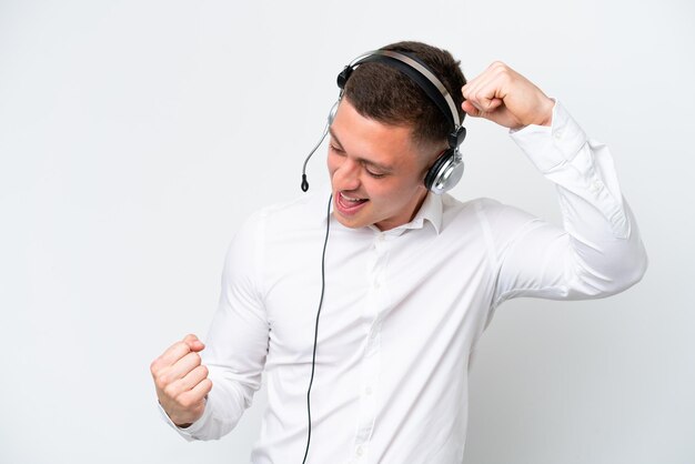 Telemarketer hombre brasileño trabajando con un auricular aislado sobre fondo blanco celebrando una victoria