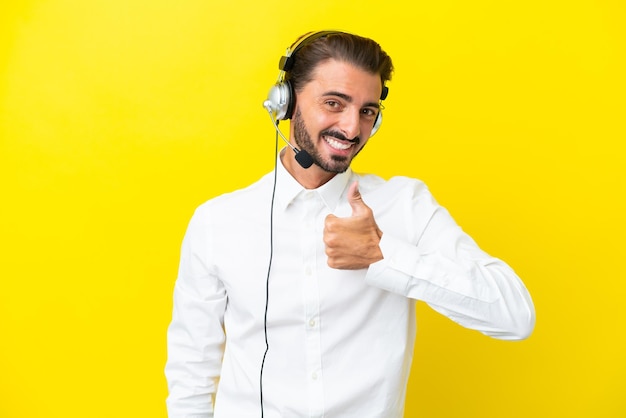Telemarketer hombre caucásico que trabaja con un auricular aislado sobre fondo amarillo dando un gesto de aprobación