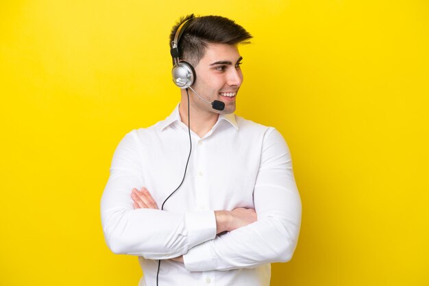 Telemarketer hombre caucásico que trabaja con un auricular aislado sobre fondo amarillo mirando hacia el lado