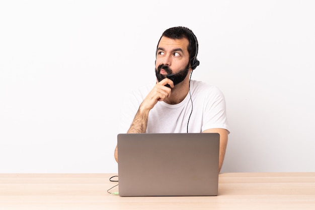 Telemarketer hombre caucásico que trabaja con un auricular y un portátil pensando en una idea mientras mira hacia arriba