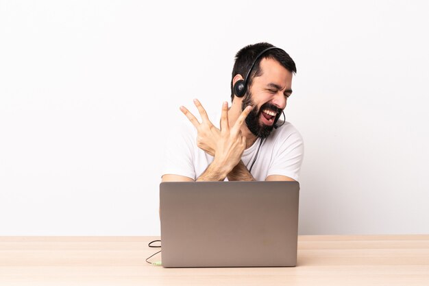 Telemarketer hombre caucásico que trabaja con un auricular y con un portátil sonriendo