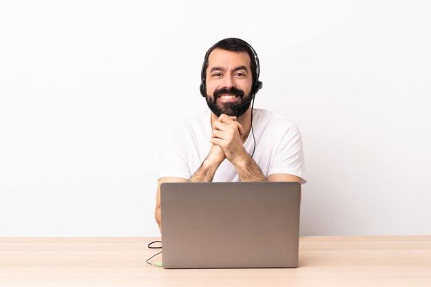 Telemarketer hombre caucásico que trabaja con auriculares y con portátil riendo