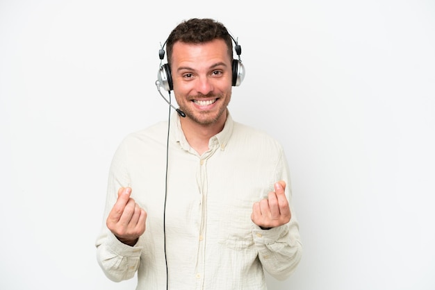 Telemarketer hombre caucásico trabajando con un auricular aislado sobre fondo blanco haciendo gesto de dinero